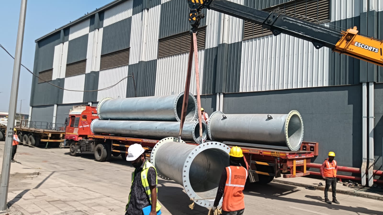 Large diameter flanged pipe spools being crane-loaded onto a flatbed truck for dispatch