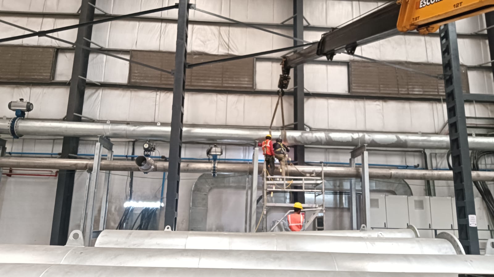 Overhead insulated pipe runs with actuated valves being installed inside an industrial facility