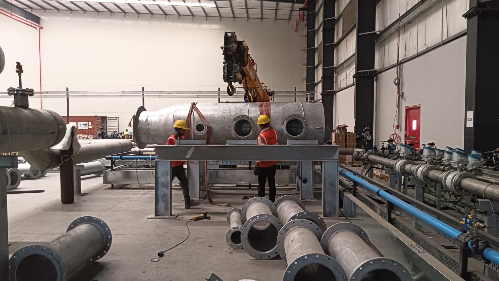 Pipe manifold and header assembly being craned onto a structural support frame on the shop floor